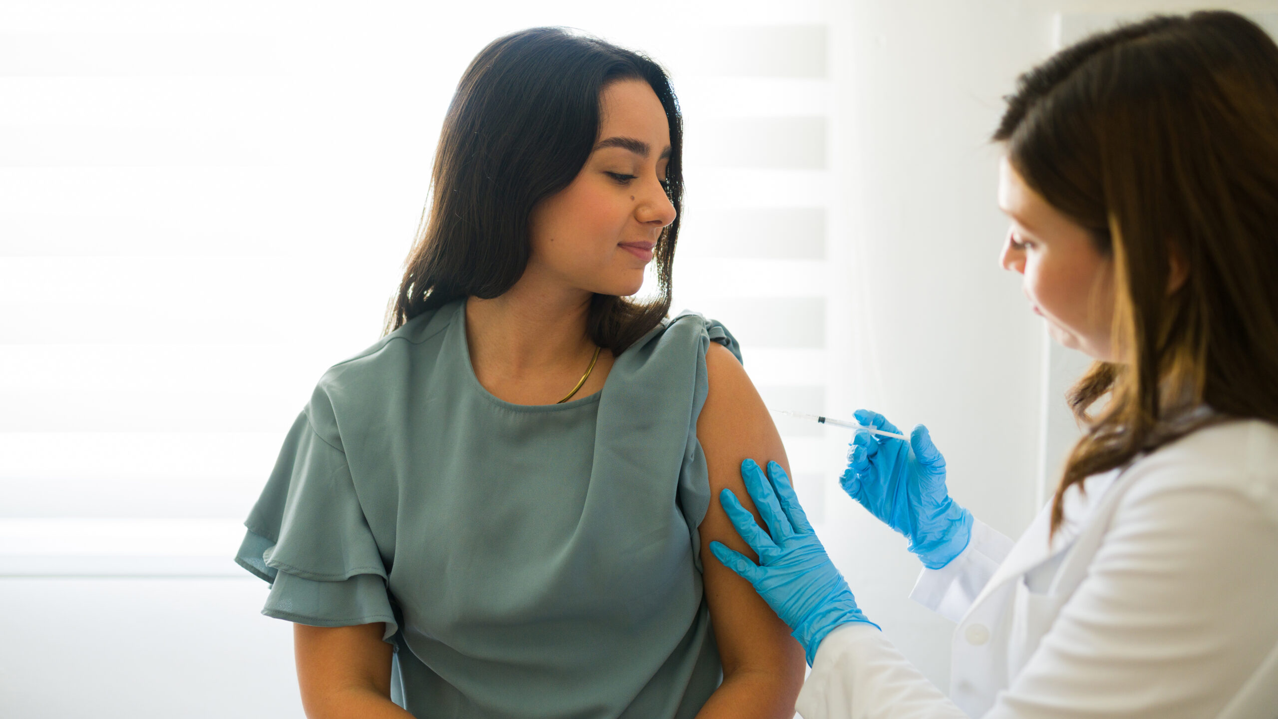 Young lady getting a vaccination from a healthcare professional in a physician's clinic