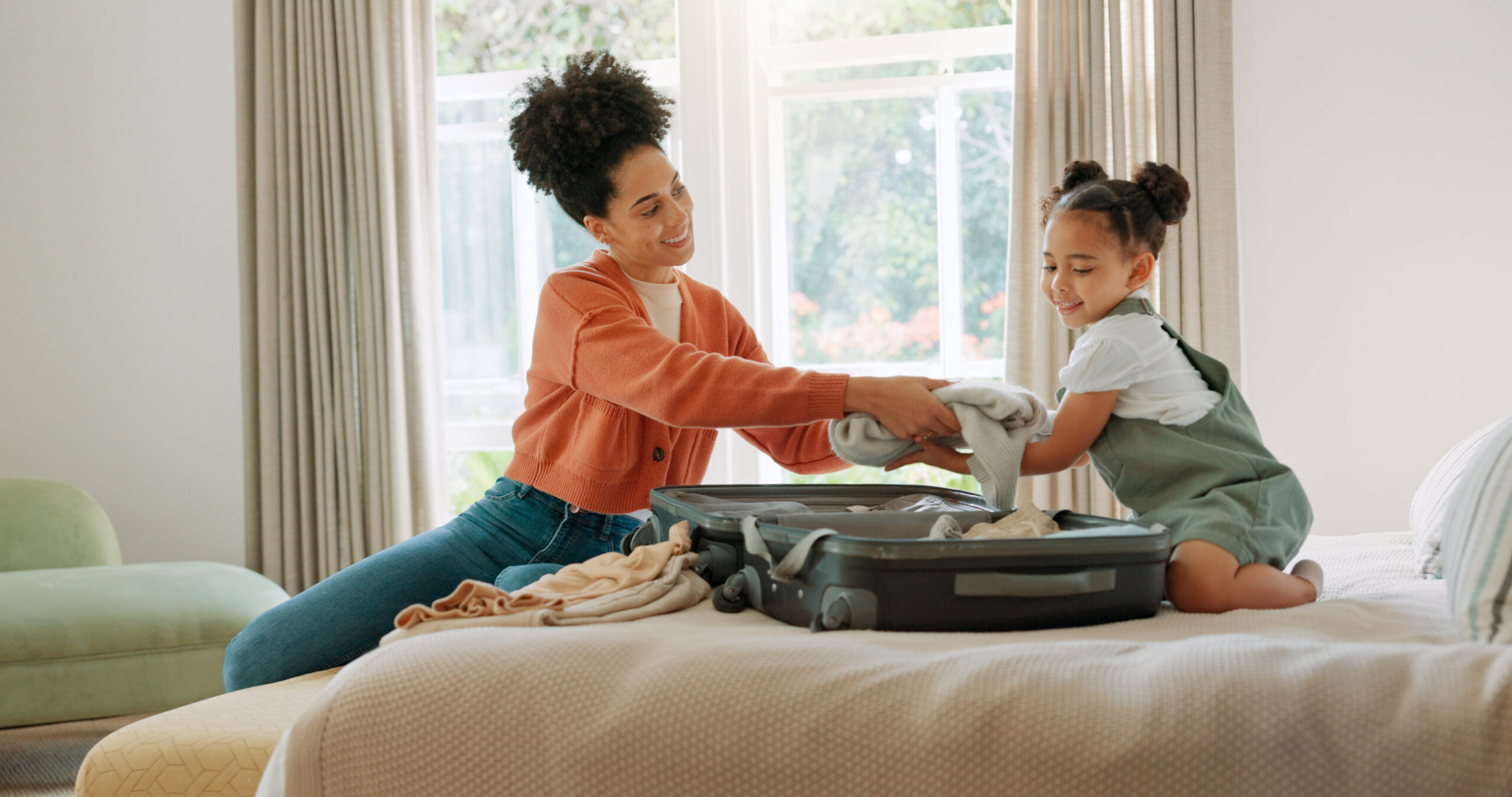 Travel, luggage and mom packing with child in bedroom getting ready for trip. Helping hands, black family and young girl help mother pack clothes in suitcase for holiday, vacation and weekend away